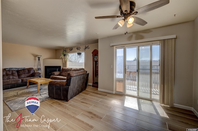 living room with a glass covered fireplace, visible vents, baseboards, and wood tiled floor