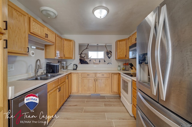 kitchen featuring a sink, light countertops, wood finish floors, and stainless steel appliances