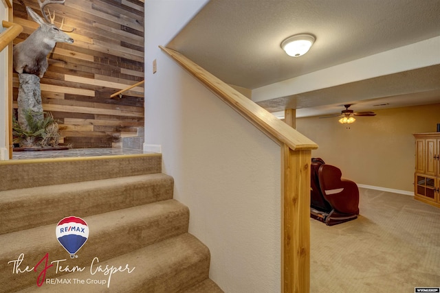 stairway featuring wooden walls and carpet flooring