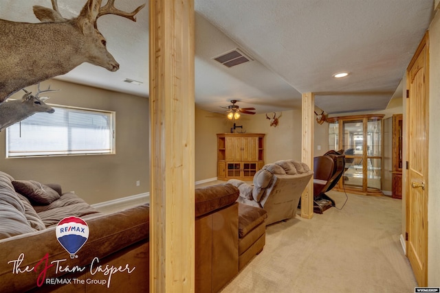 living room with visible vents, baseboards, light colored carpet, and a textured ceiling