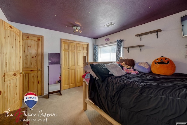 bedroom with a textured ceiling, visible vents, and light carpet