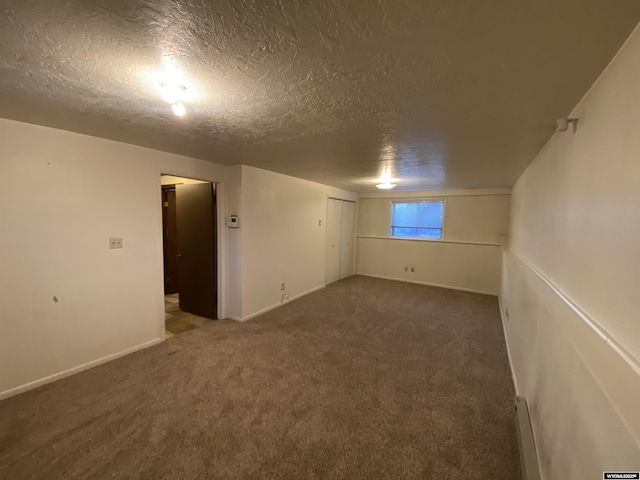 carpeted spare room with baseboards, a textured ceiling, and baseboard heating