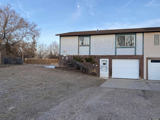 view of side of property featuring fence, a garage, and driveway