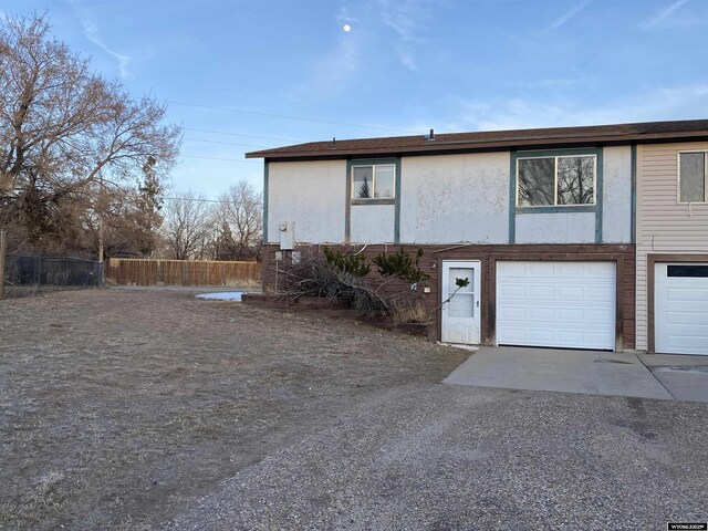 view of side of property featuring fence, a garage, and driveway