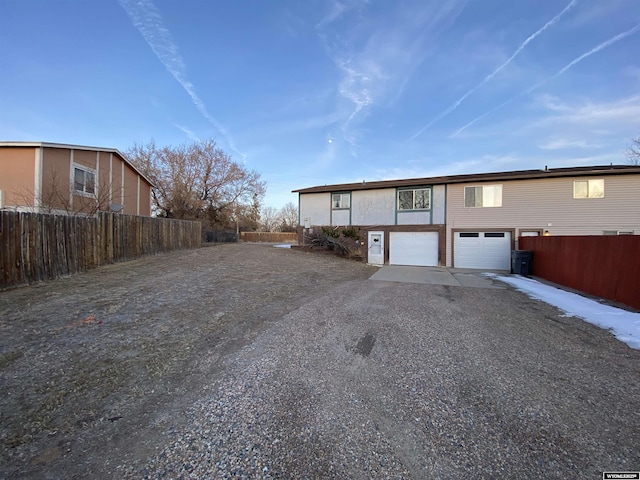 view of front of property with gravel driveway, a garage, and fence