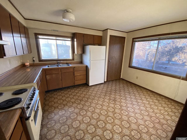 kitchen with crown molding, baseboards, tile patterned floors, white appliances, and a sink