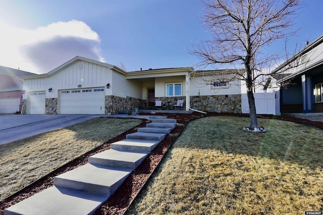 ranch-style home featuring stone siding, board and batten siding, concrete driveway, a front yard, and a garage