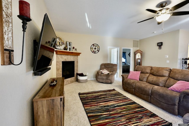 carpeted living area featuring a ceiling fan, visible vents, and a tile fireplace