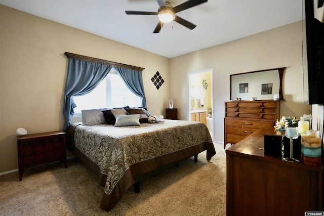 bedroom featuring connected bathroom, baseboards, light colored carpet, and a ceiling fan