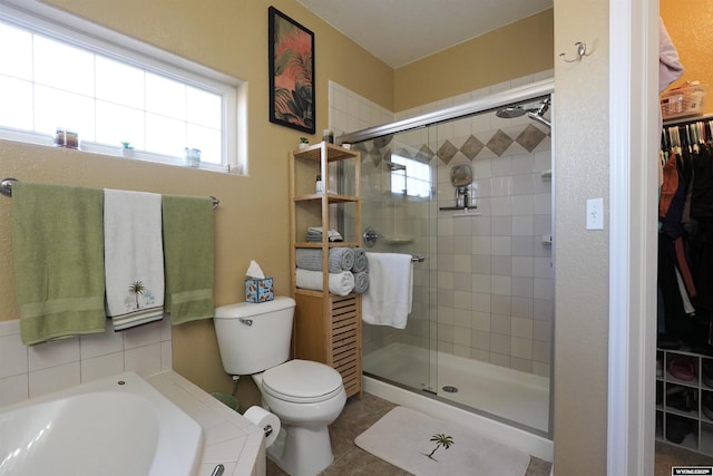 full bathroom with a walk in closet, a shower stall, toilet, and a bath