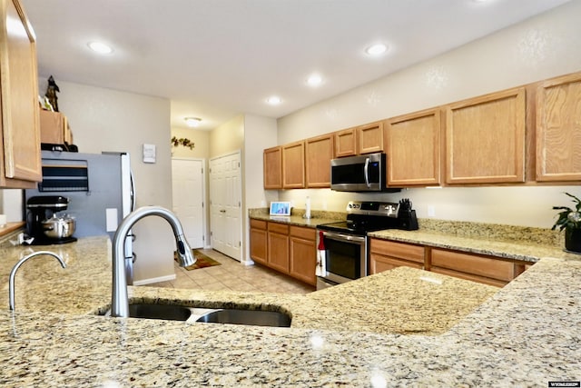 kitchen featuring a sink, light stone countertops, appliances with stainless steel finishes, and light tile patterned floors