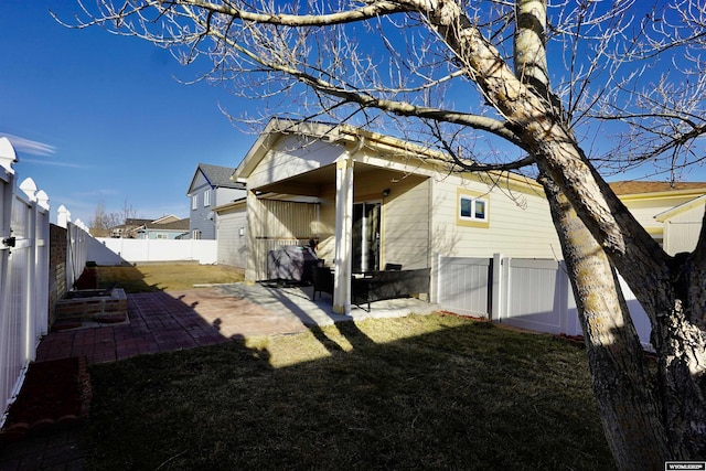 rear view of house featuring a fenced backyard, a lawn, and a patio