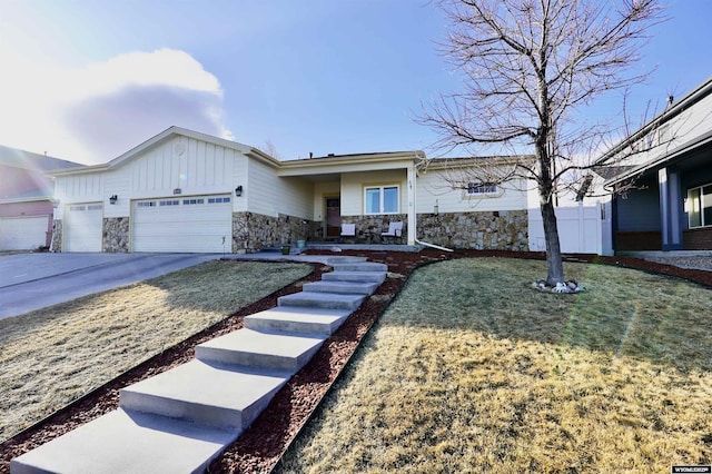 ranch-style home with driveway, stone siding, board and batten siding, a front yard, and an attached garage