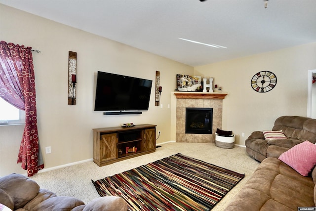 carpeted living room with a tiled fireplace and baseboards