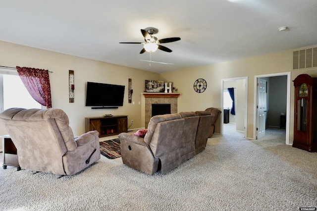 carpeted living area with a tile fireplace, visible vents, and ceiling fan