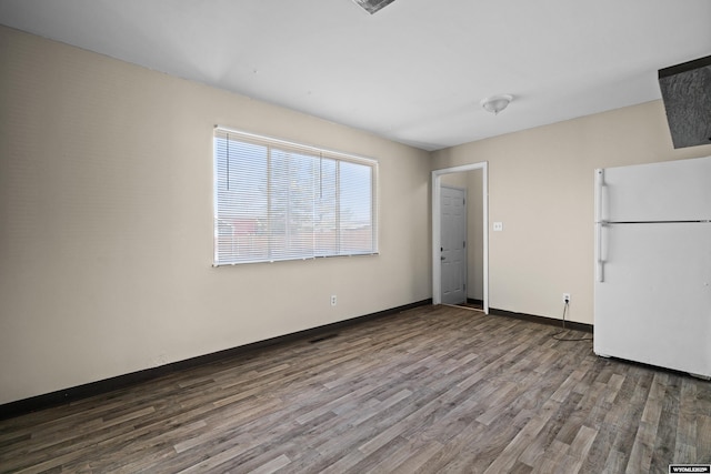 interior space featuring baseboards, wood finished floors, and freestanding refrigerator