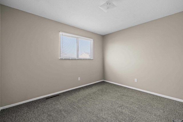 unfurnished room featuring visible vents, baseboards, a textured ceiling, and dark carpet