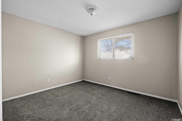 unfurnished room with baseboards, dark colored carpet, and a textured ceiling