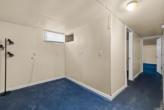 basement with baseboards and wood walls