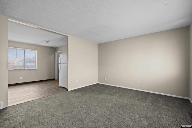 unfurnished room featuring baseboards, dark colored carpet, and a textured ceiling