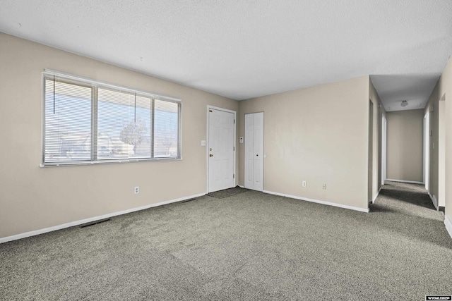 carpeted empty room with baseboards and a textured ceiling