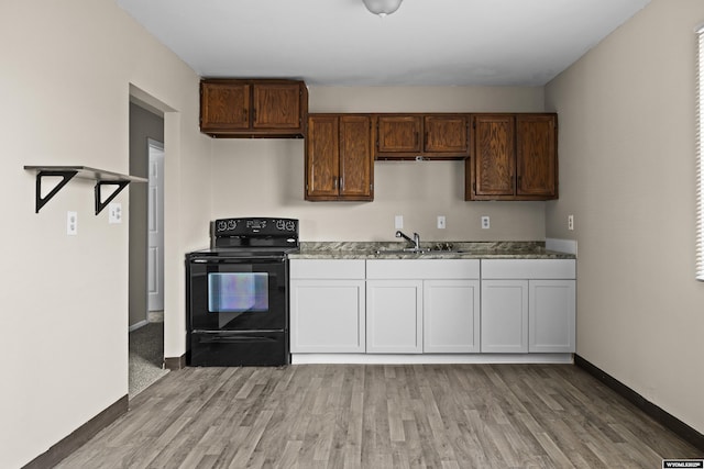 kitchen featuring a sink, baseboards, black range with electric cooktop, and light wood finished floors