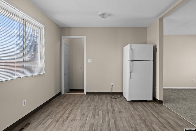 interior space with visible vents, freestanding refrigerator, baseboards, and wood finished floors