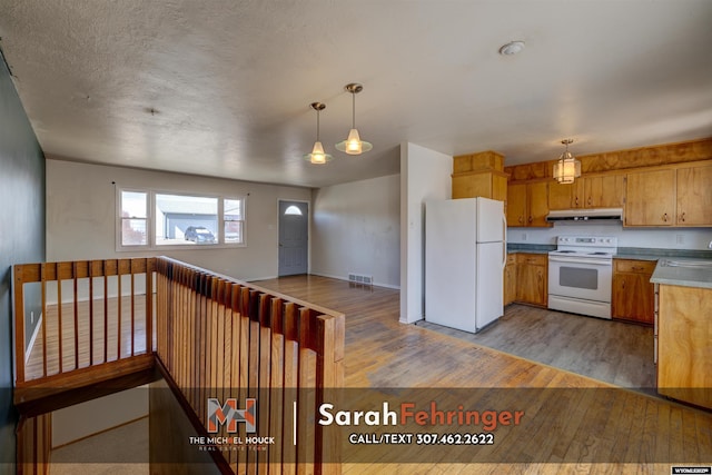 kitchen with visible vents, under cabinet range hood, a sink, wood finished floors, and white appliances