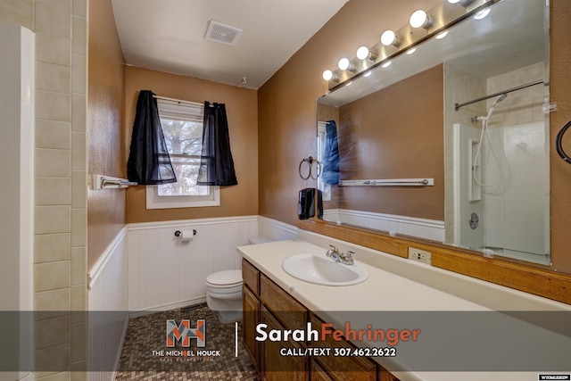 full bath featuring visible vents, a wainscoted wall, toilet, walk in shower, and vanity