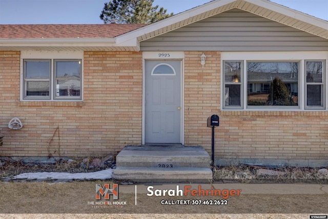 property entrance with brick siding and roof with shingles