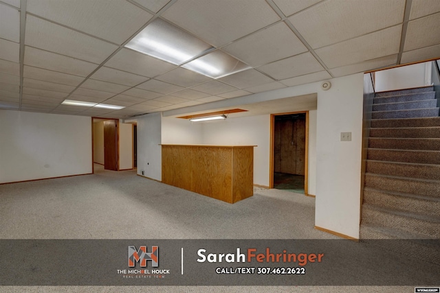 finished below grade area featuring carpet, stairway, a paneled ceiling, and baseboards