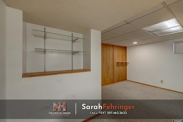 interior space featuring a paneled ceiling and baseboards