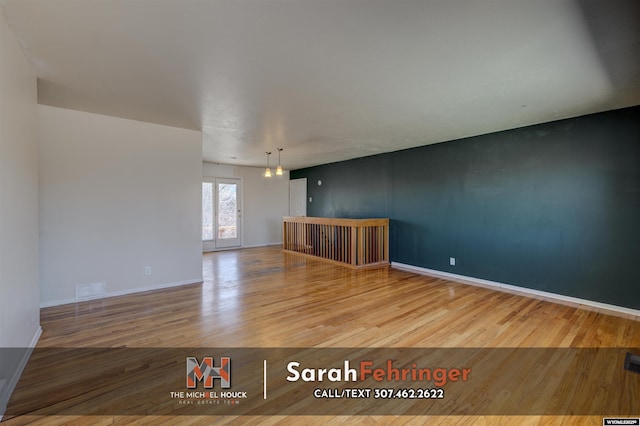 unfurnished room with a chandelier, visible vents, baseboards, and wood finished floors