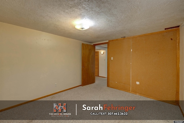 empty room with baseboards, a textured ceiling, and carpet