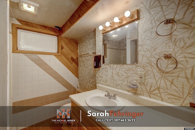 bathroom with vanity and wallpapered walls