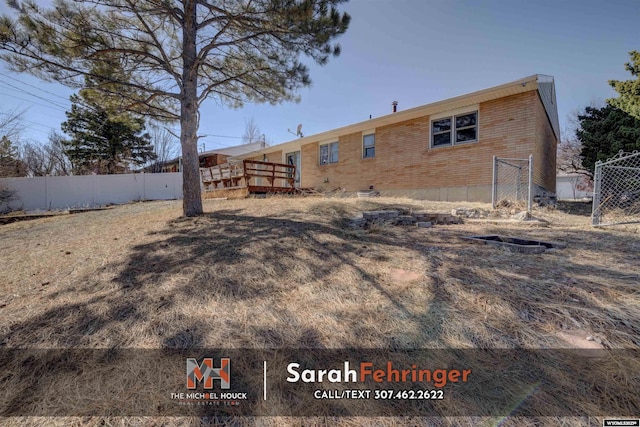 back of property with brick siding and fence