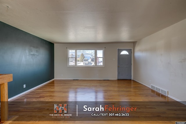 foyer entrance with wood finished floors, visible vents, and baseboards