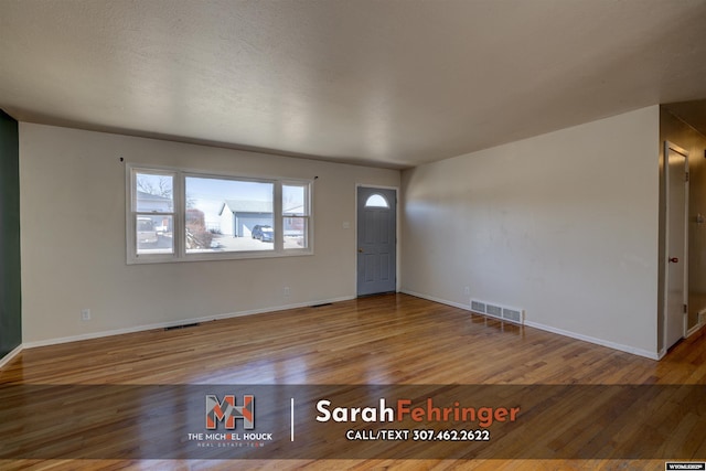 foyer featuring wood finished floors, visible vents, and baseboards