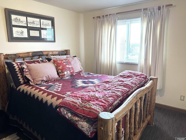 bedroom featuring baseboards and dark carpet