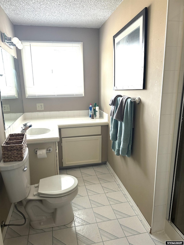 full bathroom with a shower with door, baseboards, toilet, vanity, and a textured ceiling