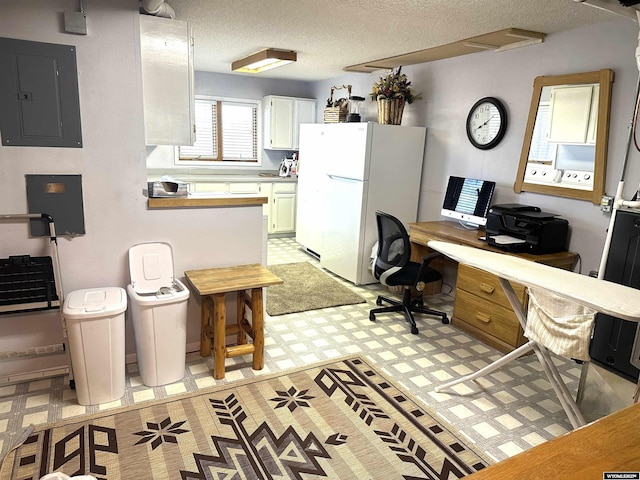 kitchen featuring light floors, electric panel, freestanding refrigerator, light countertops, and a textured ceiling