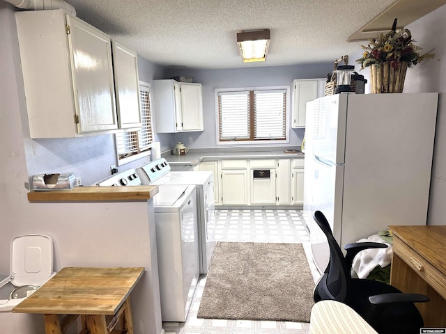 washroom featuring washing machine and clothes dryer, laundry area, light floors, and a textured ceiling