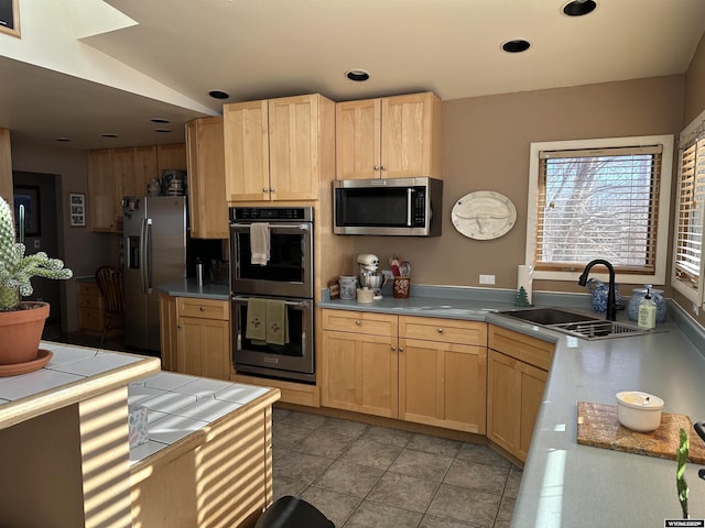 kitchen featuring light brown cabinetry, light tile patterned floors, appliances with stainless steel finishes, and a sink