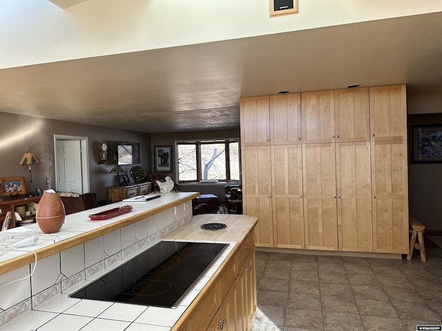 kitchen featuring tile patterned flooring, black electric stovetop, light brown cabinetry, and tile countertops