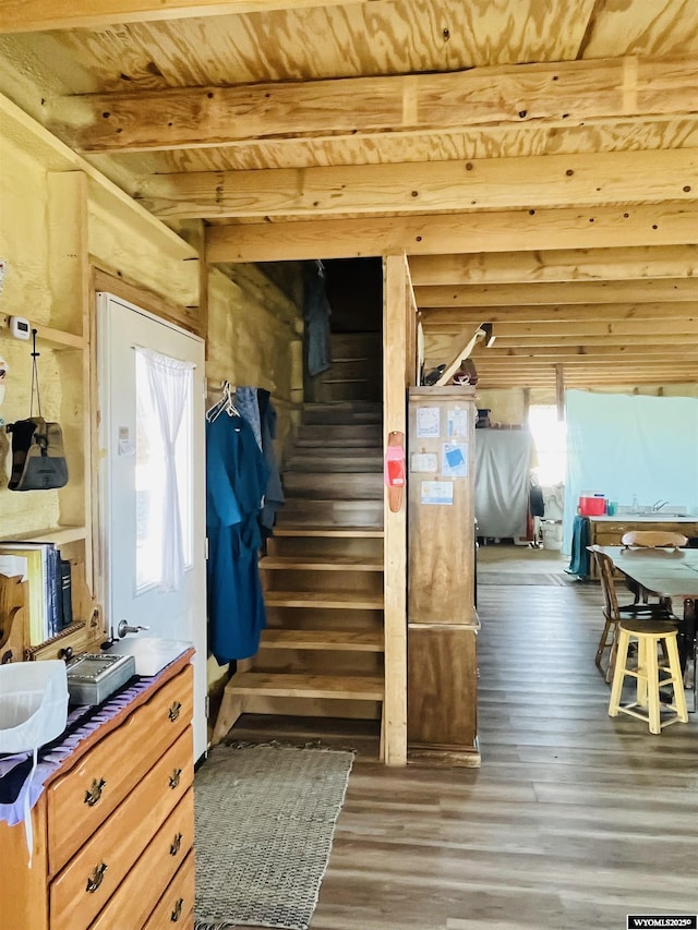 stairway with beam ceiling, wood ceiling, and wood finished floors