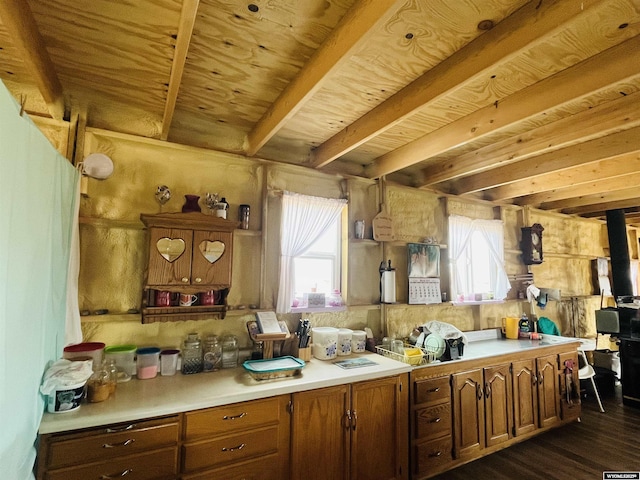 kitchen featuring brown cabinetry, dark wood-style floors, light countertops, wooden ceiling, and beamed ceiling