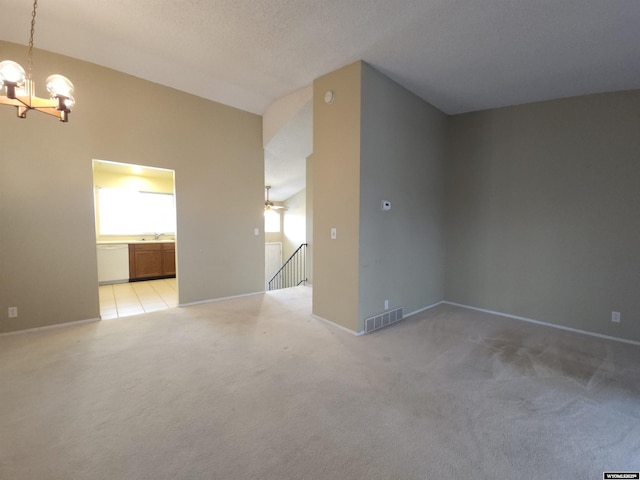 unfurnished living room with visible vents, baseboards, light colored carpet, ceiling fan with notable chandelier, and a sink