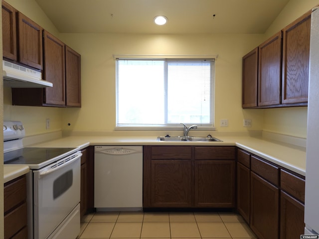 kitchen featuring under cabinet range hood, light countertops, light tile patterned floors, white appliances, and a sink