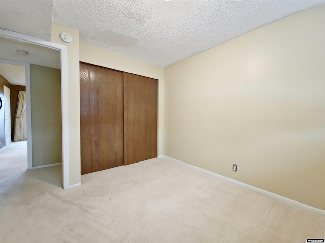 unfurnished bedroom with baseboards, carpet, a closet, and a textured ceiling