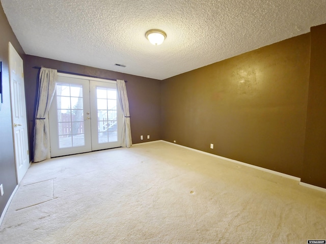 empty room featuring french doors, carpet floors, a textured ceiling, and baseboards